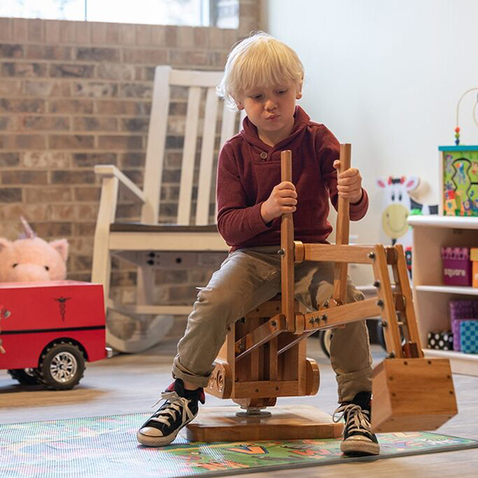 Young boy playing on a wooden toy